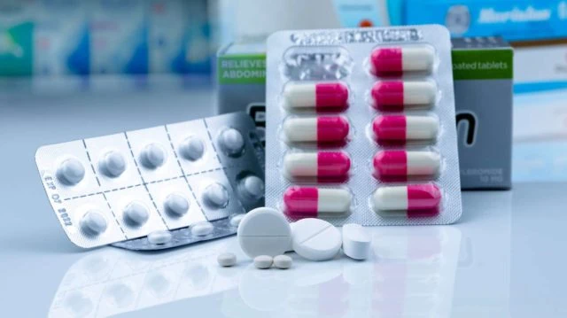 Pills in pharmacy shop. White tablets pills on blurred capsule i